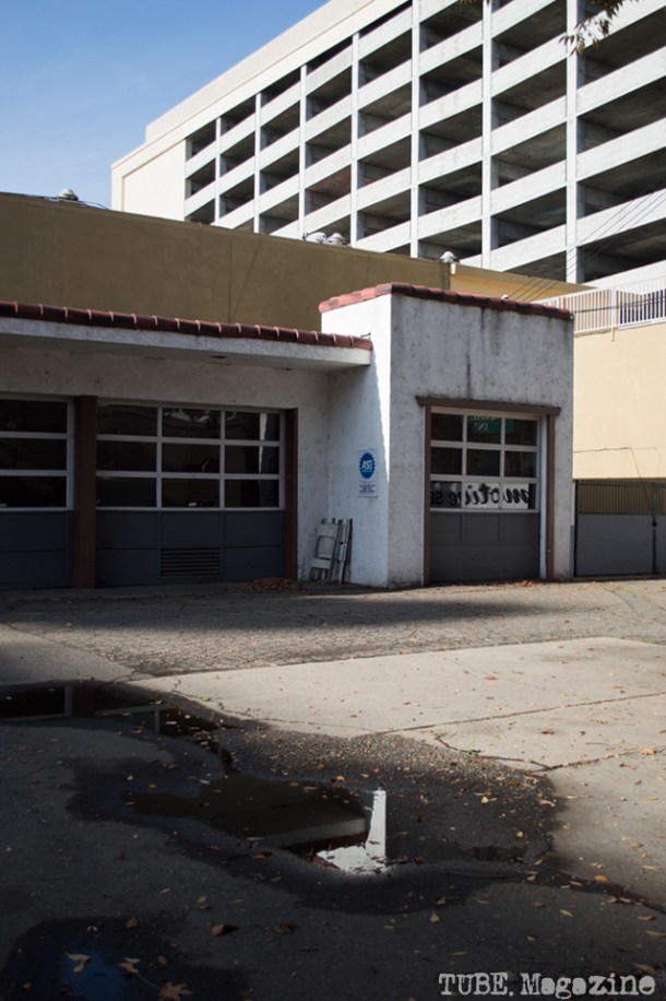 A city parking structure rises behind a vacant autobody shop on I Street. Photo M.Hershenow. 2014.